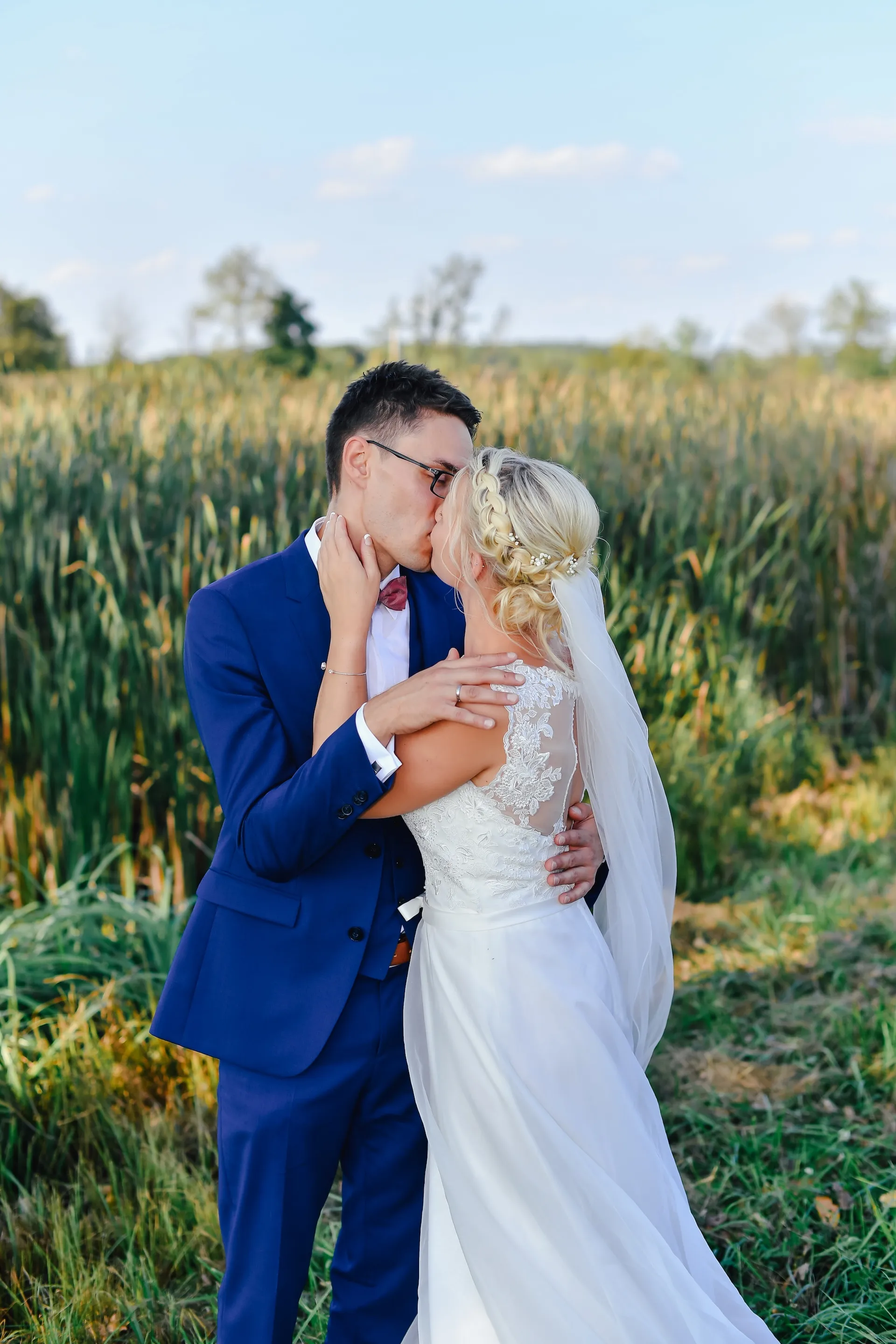 Brautpaar küsst sich auf dem Feld
