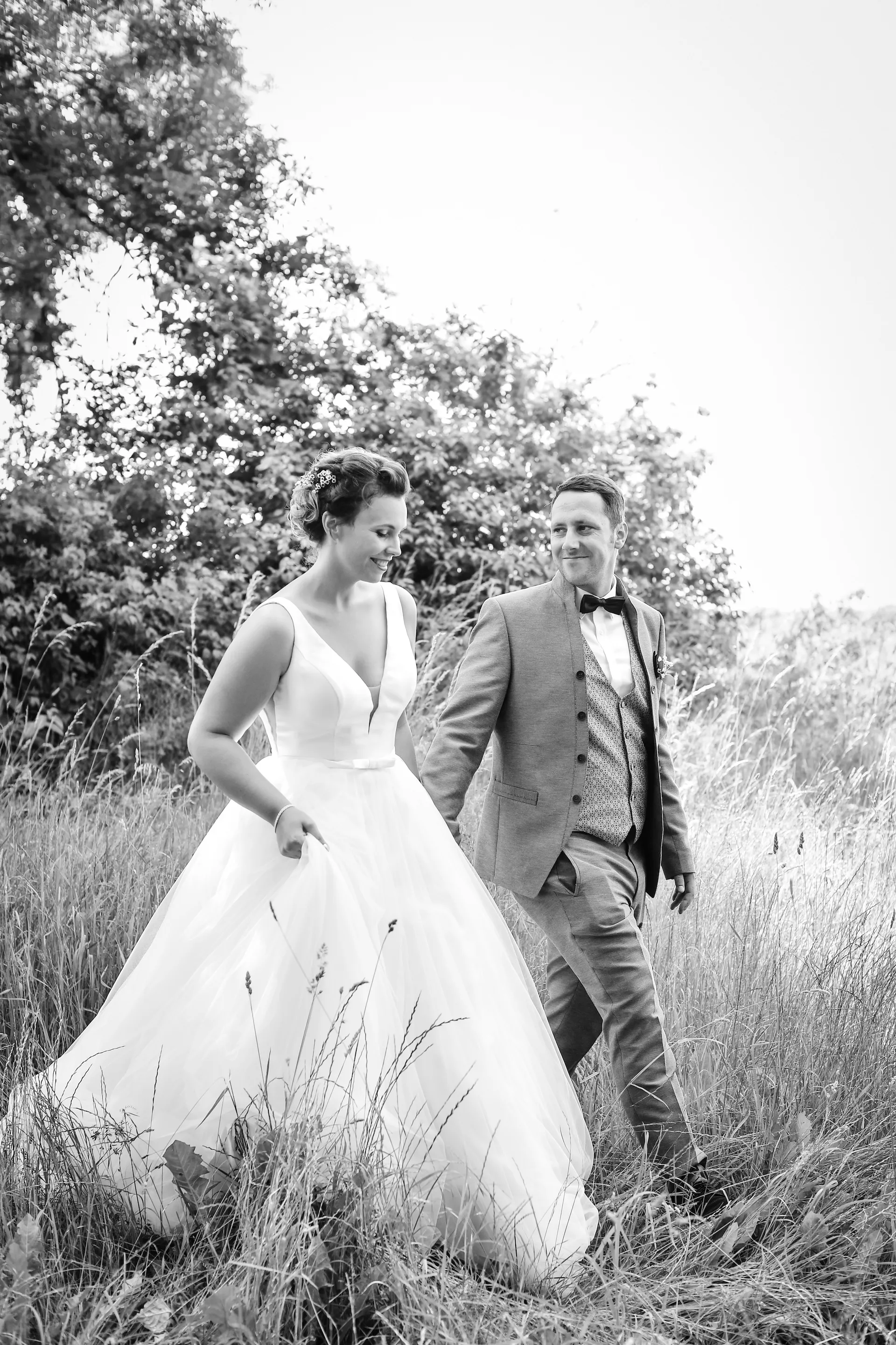 Brautpaar läuft durch hohes Gras Schwarzweiß