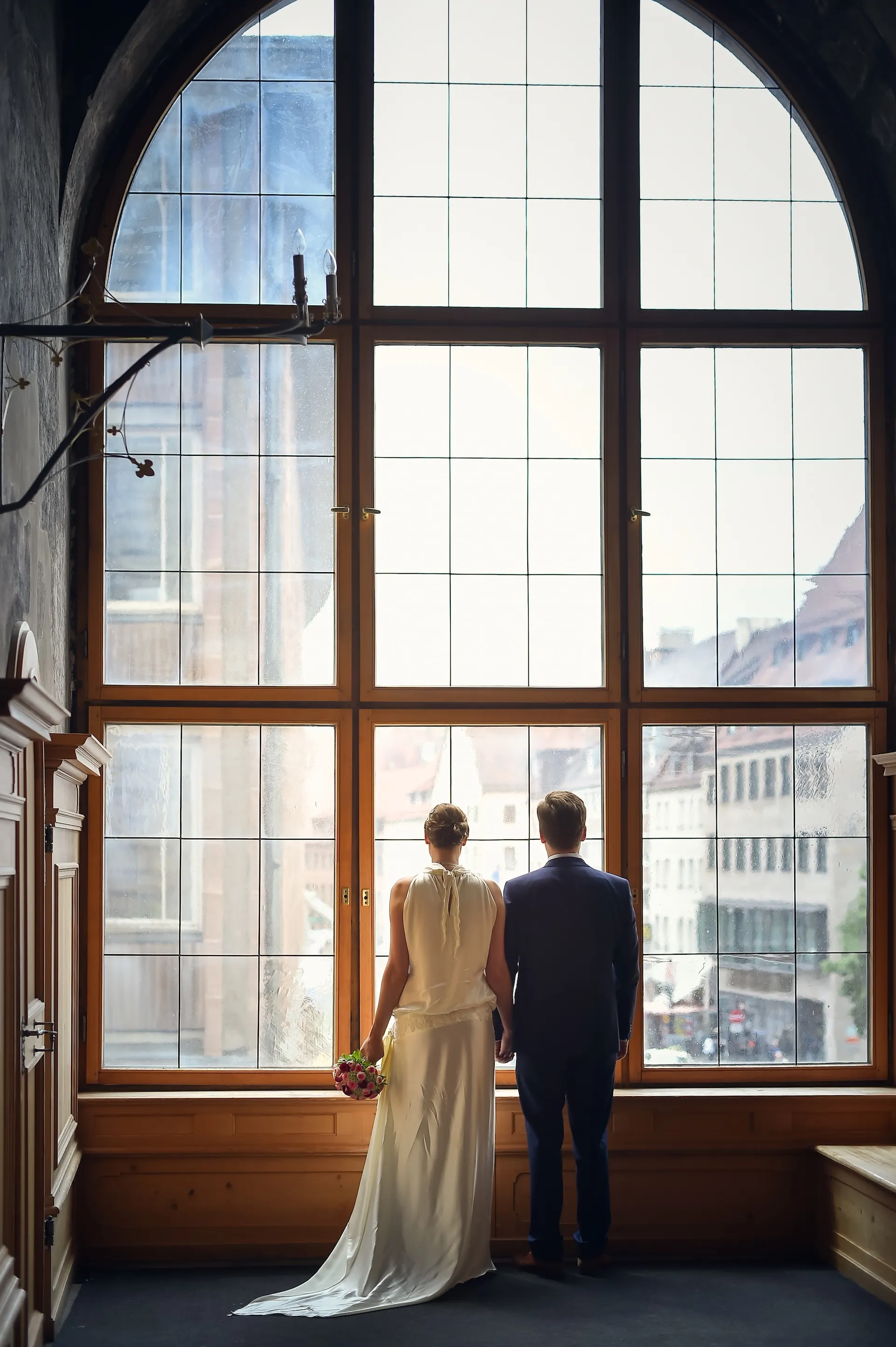 Brautpaar von hinten vor großem Fenster